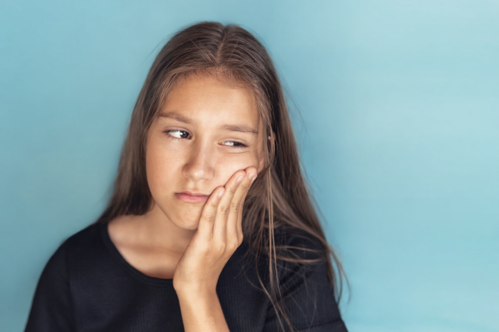 A little girl has a sore inner cheek because one of her baby teeth is broken.