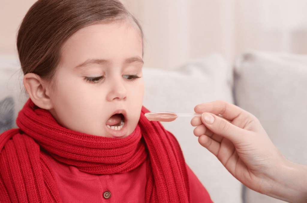 A little girl is taking age-appropriate liquid ibuprofen at the recommended dosage after her baby tooth injury.