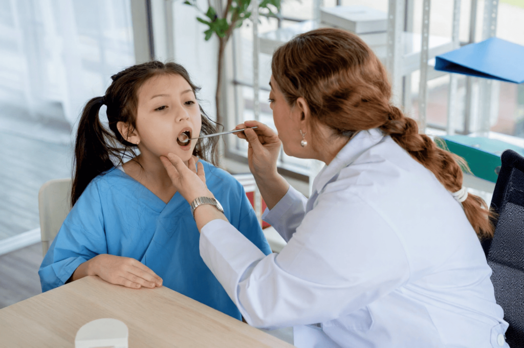 A dentist is checking a little girl's chipped tooth.