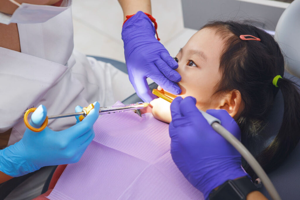 A little girl shows willingness to open their mouth and sit still during a dental treatment.