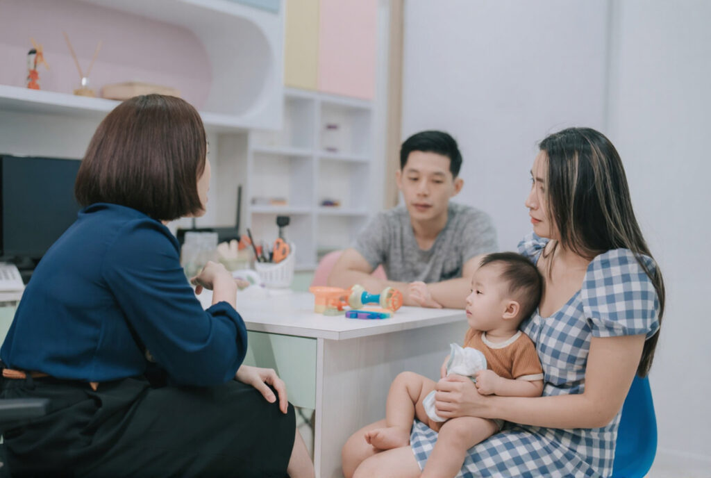 A doctor is consulting with parents about a frenectomy to treat their child's tongue-tie.
