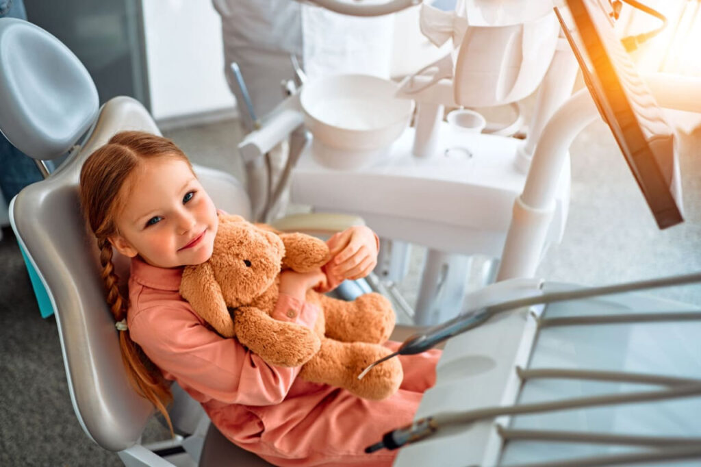 A mother prepares a teddy bear for her little girl to bring along to the dentist.