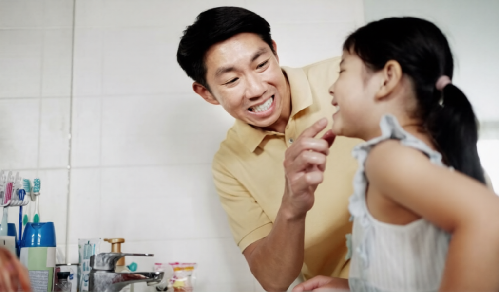A father is checking white spots on his child’s upper front teeth.