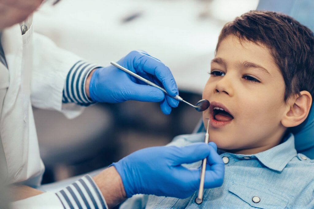 A dentist is examining white spots on a child’s teeth to categorize the spots and select a treatment plan.