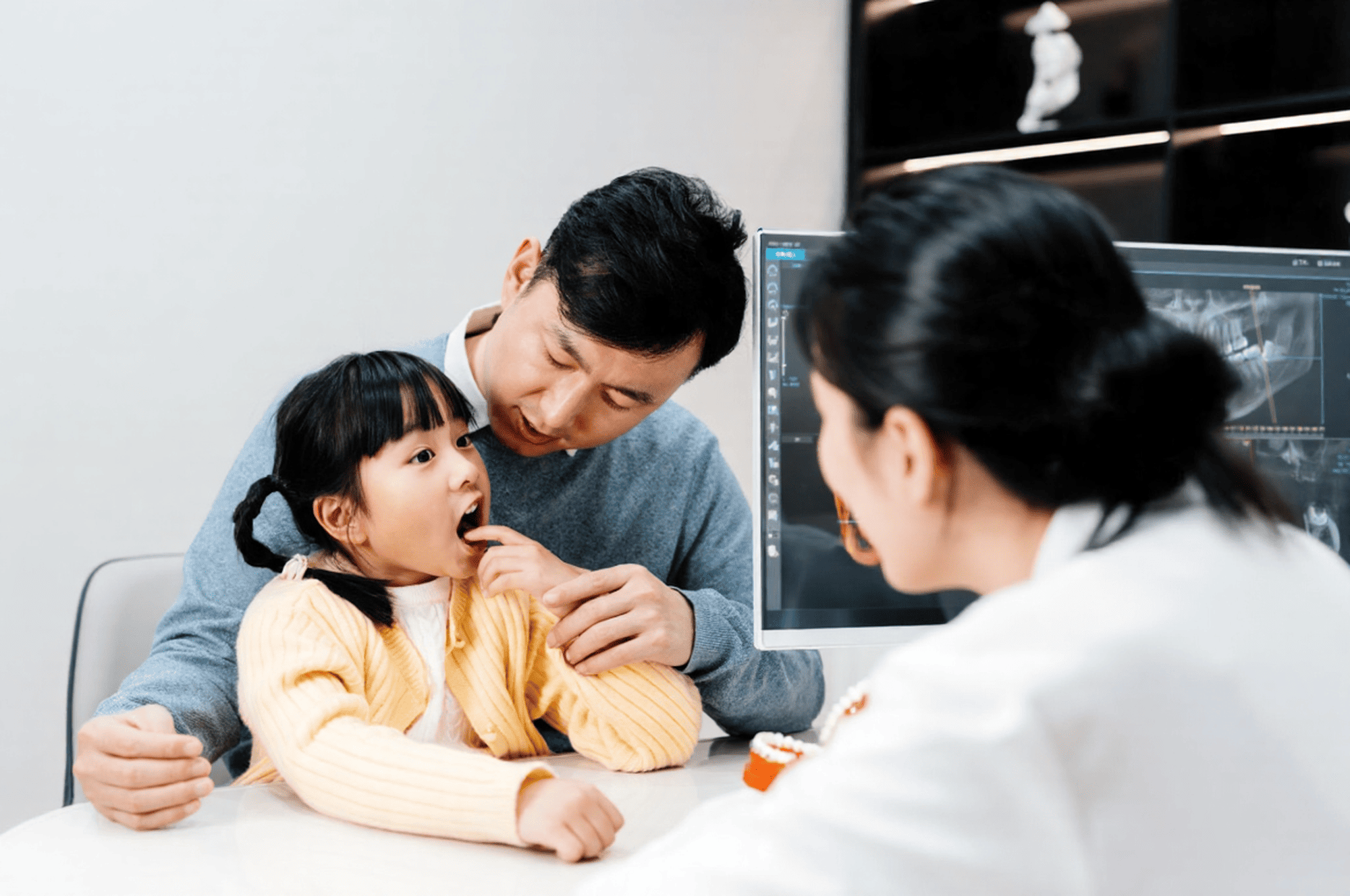 A parent is listening to the dentist explain her child's delayed teething.