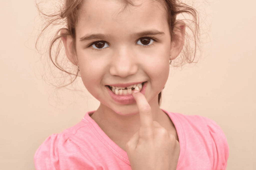 A little girl has a tooth that hasn't come in for a long time.